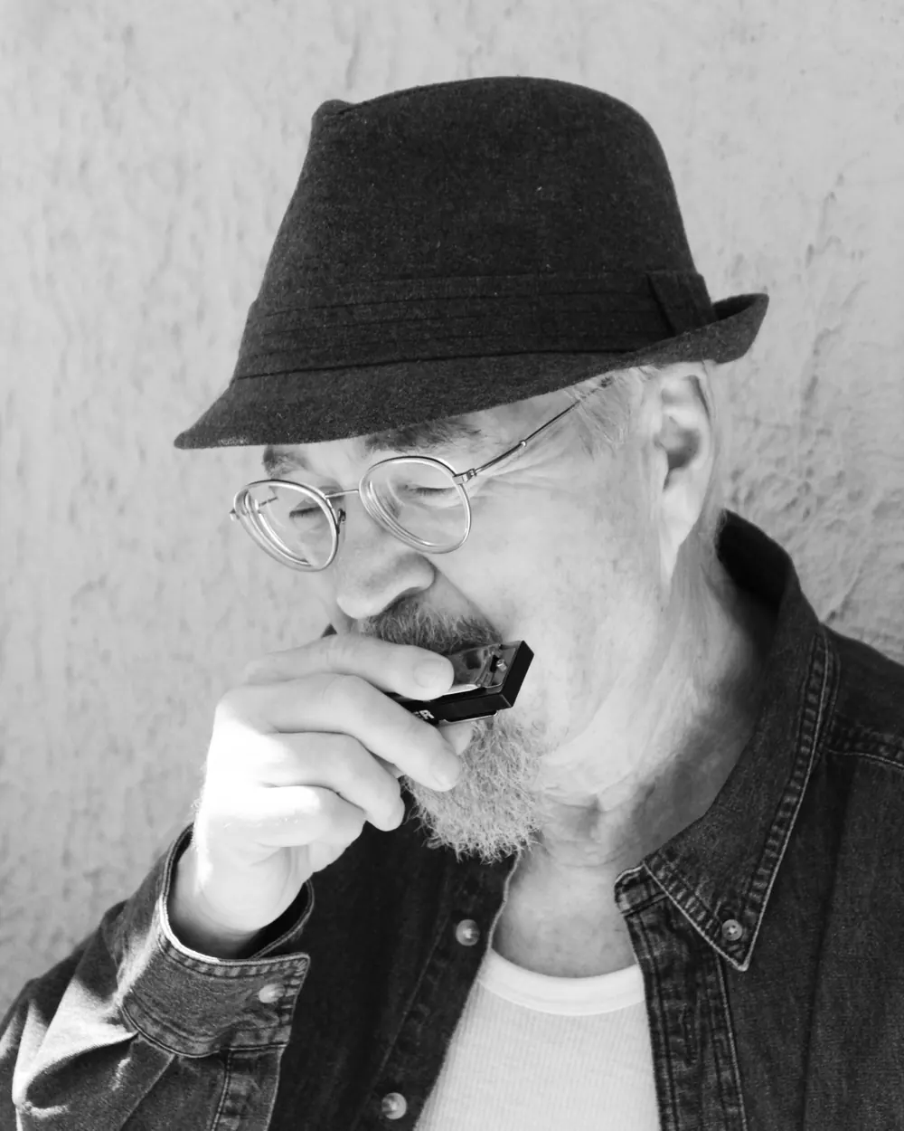 Black-and-white portrait of Rich Cloud in a fedora, playing harmonica